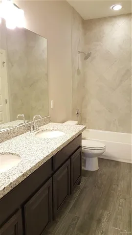 a bathroom with a granite countertop toilet a sink and a bathtub