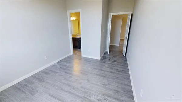 a view of an empty room with wooden floor and closet
