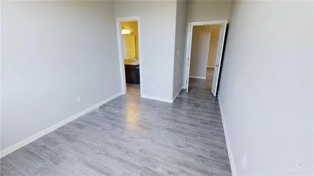 a view of an empty room with wooden floor and closet