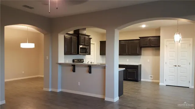 a view of a kitchen with a sink and dishwasher a stove top oven with wooden floor