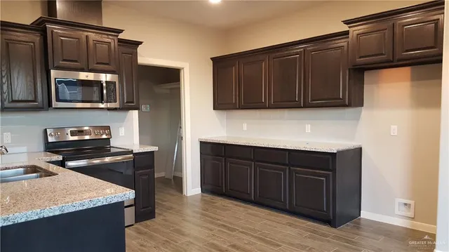 a kitchen with stainless steel appliances granite countertop wooden cabinets and a stove top oven