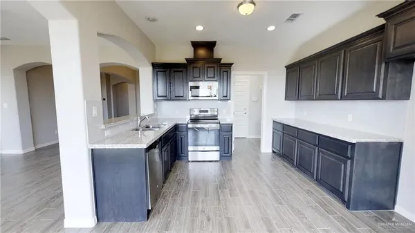 a kitchen with stainless steel appliances granite countertop wooden cabinets a stove top oven a sink and dishwasher