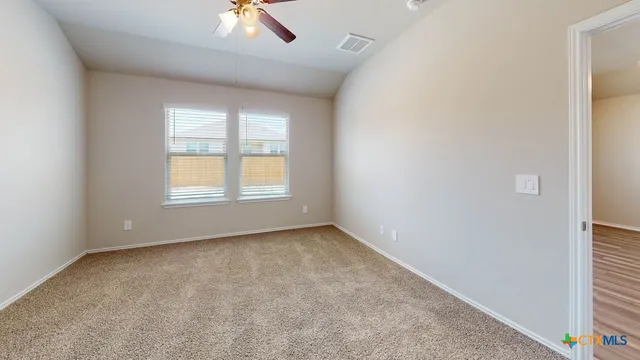 an empty room with a window and a ceiling fan