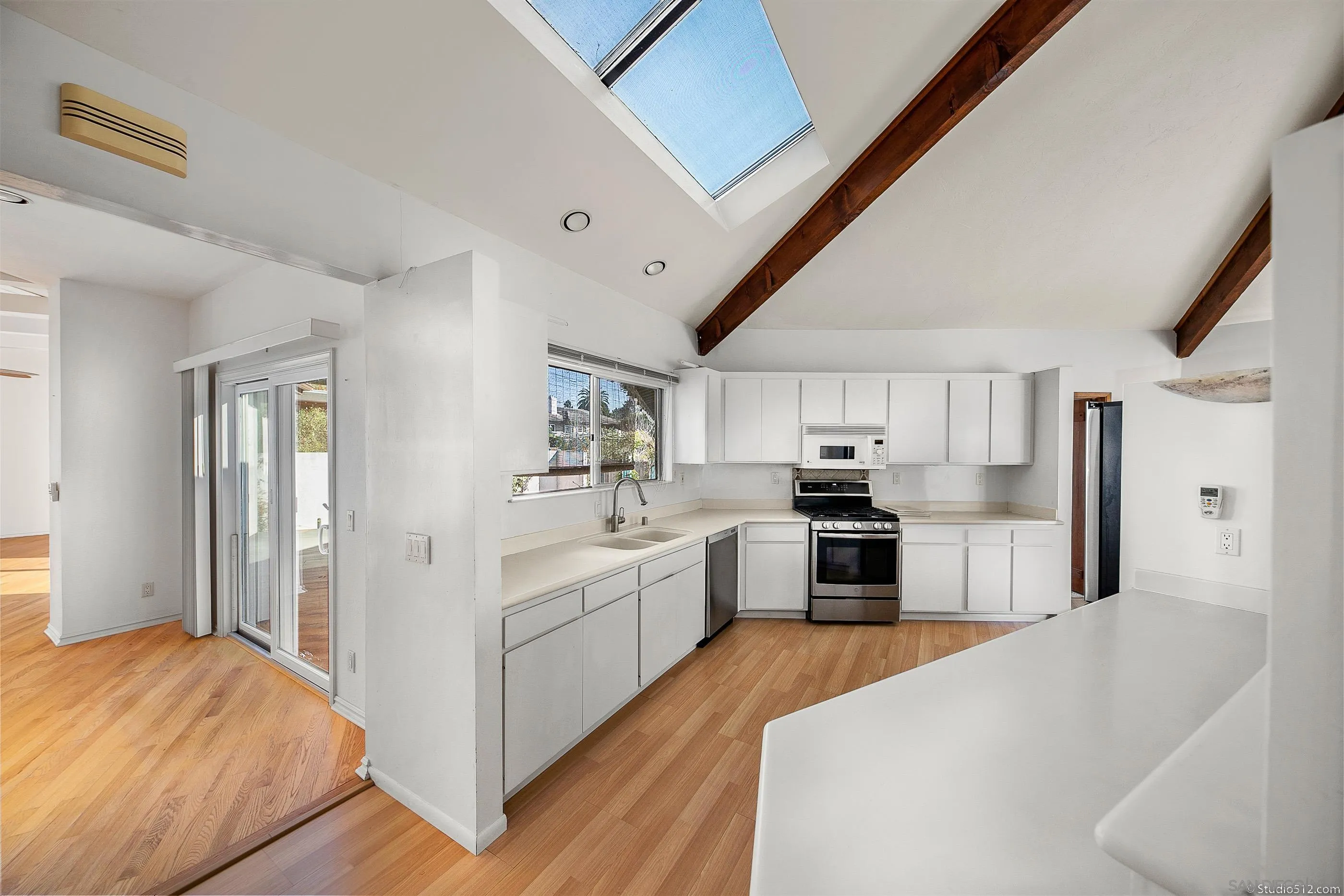 1112 Oceanic Drive Encinitas, CA 92024 - Photo 7 of 32 a large white kitchen with cabinets and wooden floor
