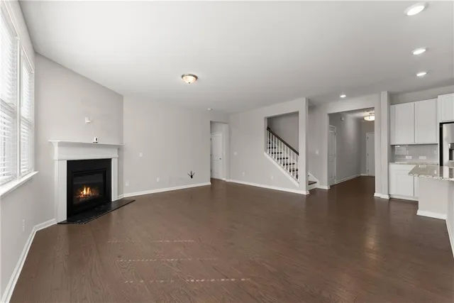 a view of an empty room with wooden floor a fireplace
