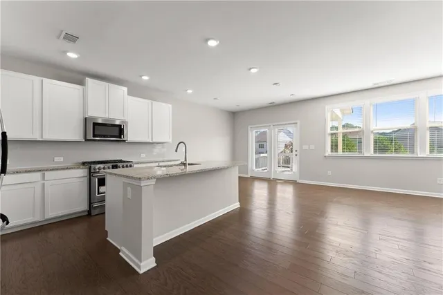 a large kitchen with stainless steel appliances granite countertop a stove a sink dishwasher and a microwave oven with wooden floor