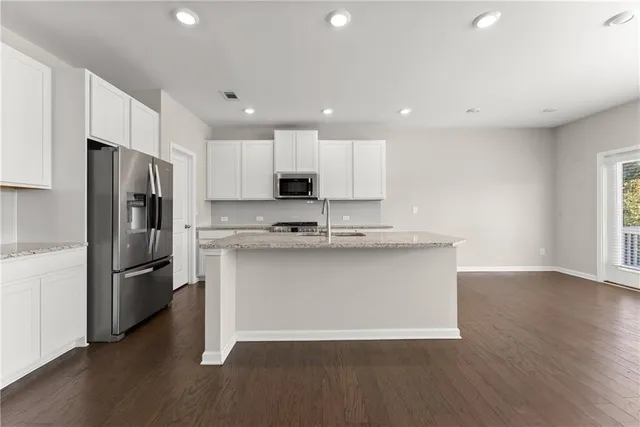 a large kitchen with stainless steel appliances a refrigerator and a stove top oven