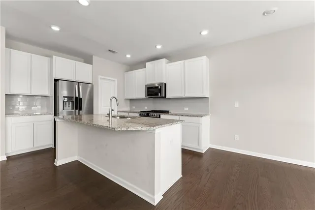 a kitchen with stainless steel appliances granite countertop a refrigerator sink and white cabinets