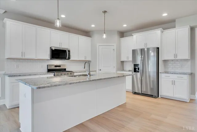 a kitchen with kitchen island granite countertop a sink appliances and cabinets