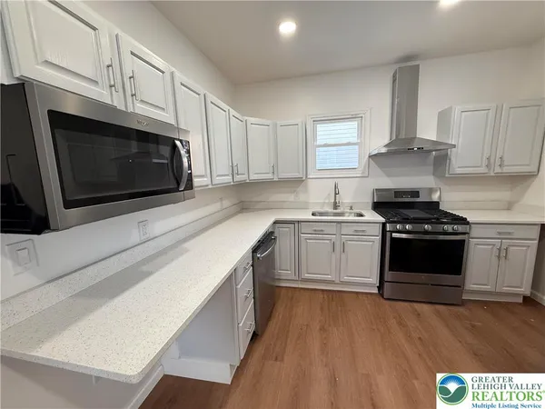 a kitchen with stainless steel appliances white cabinets and wooden floor