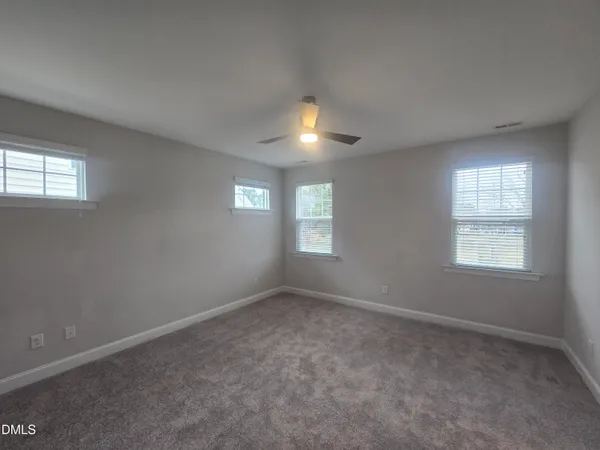 an empty room with windows and fan