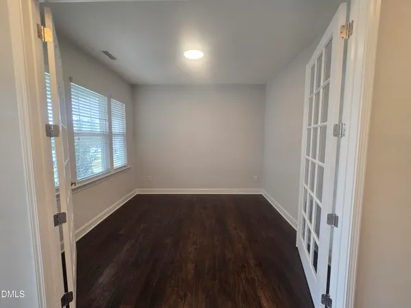 a view of an empty room with wooden floor and a window