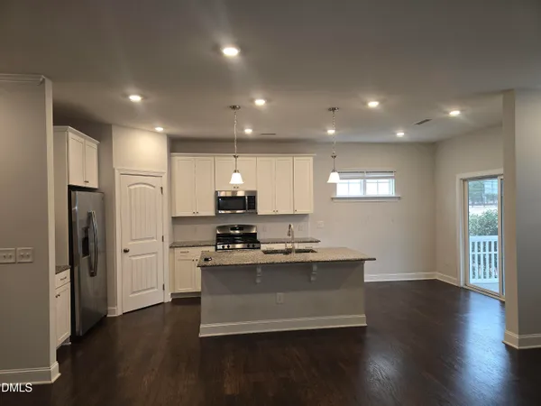 a kitchen with stainless steel appliances granite countertop a refrigerator a sink dishwasher a stove and a wooden floors