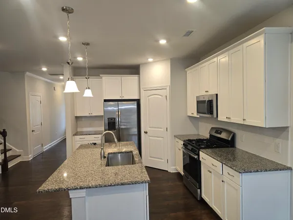 a kitchen with stainless steel appliances granite countertop a sink a stove and a refrigerator