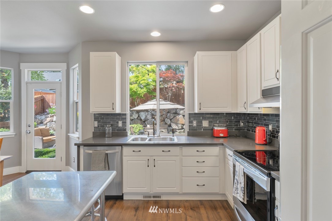 5030 Northeast 4th Place Renton, WA 98059 - Photo 14 of 35 a kitchen with stainless steel appliances a white stove top oven a sink a chimney and a cabinets