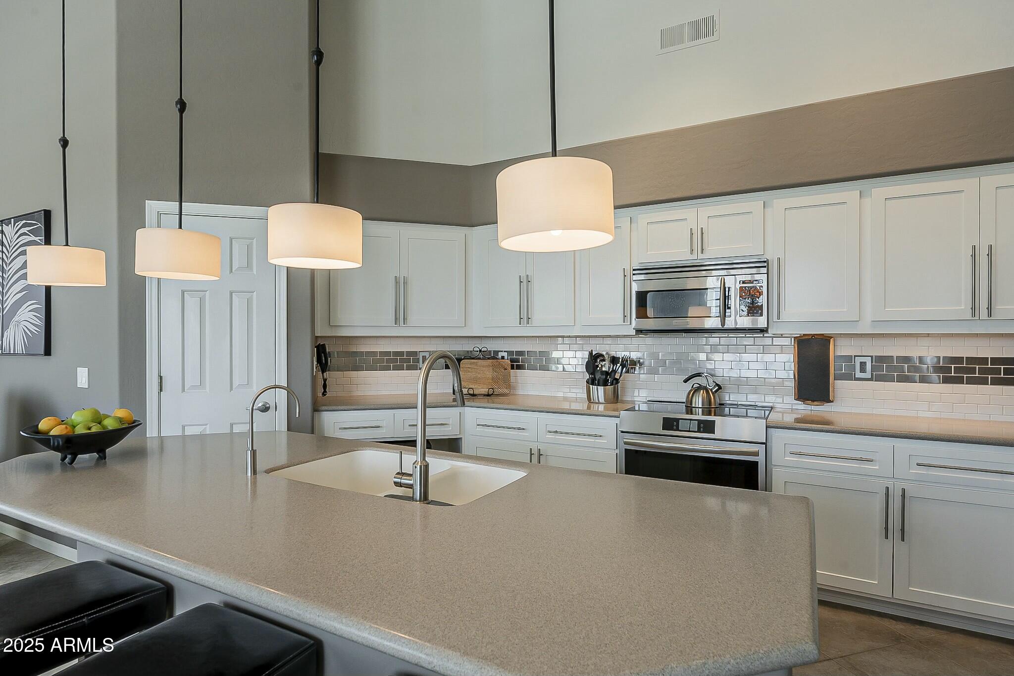 6334 East Viewmont Drive, Unit 29 Mesa, AZ 85215 - Photo 11 of 47 a kitchen with stainless steel appliances a sink a stove and white cabinets