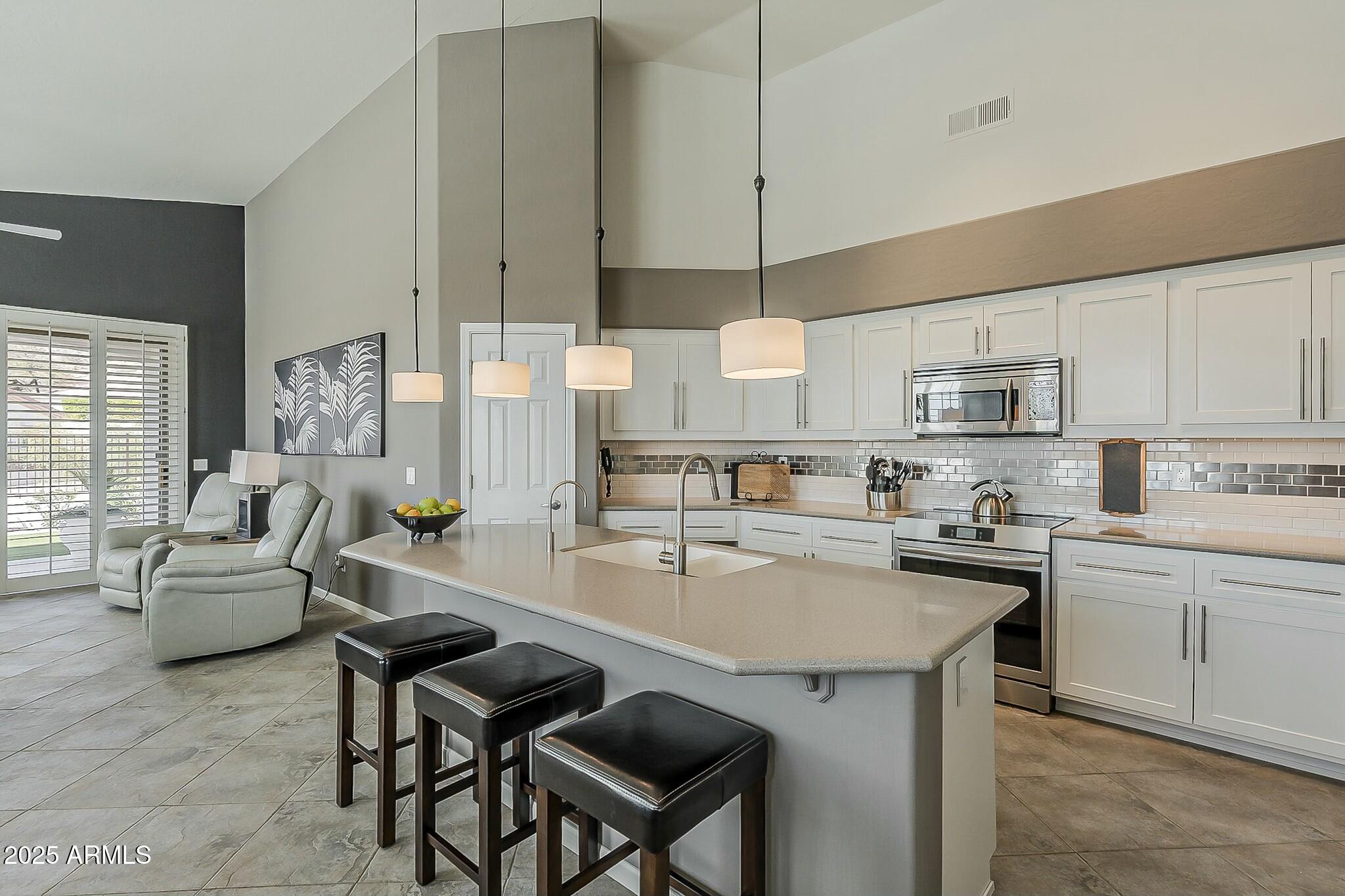 6334 East Viewmont Drive, Unit 29 Mesa, AZ 85215 - Photo 14 of 47 a kitchen with stainless steel appliances granite countertop a stove a sink a microwave a dining table and chairs with white cabinets