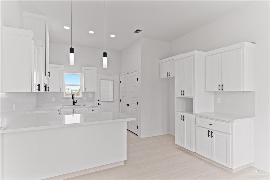 1925 Trinity Street Donna, TX 78537 - Photo 6 of 20 a large white kitchen with kitchen island a sink a stove and white cabinets