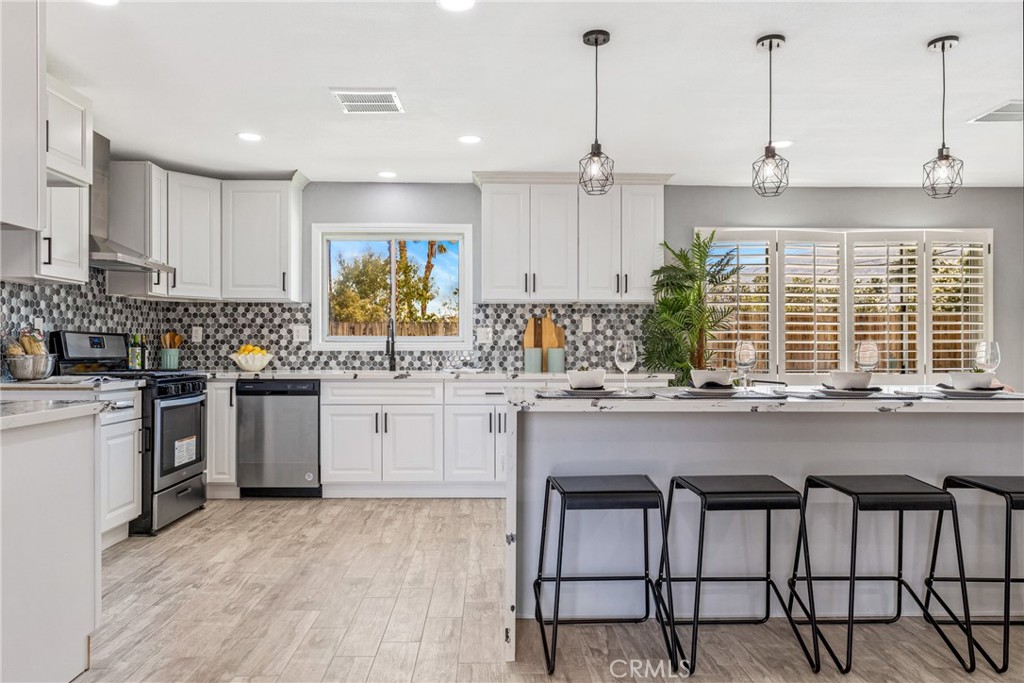 373 East Simms Road Palm Springs, CA 92262 - Photo 23 of 24 a kitchen with kitchen island granite countertop a stove a sink and white cabinets