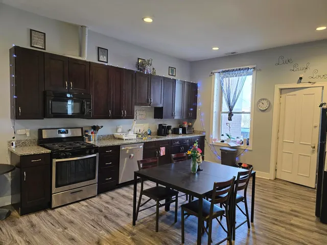 a kitchen with granite countertop wooden cabinets dining table and stainless steel appliances