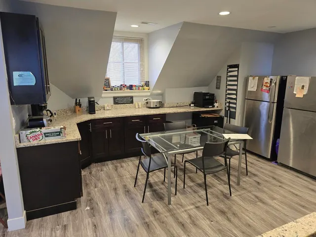 a kitchen with stainless steel appliances granite countertop a table chairs sink and cabinets