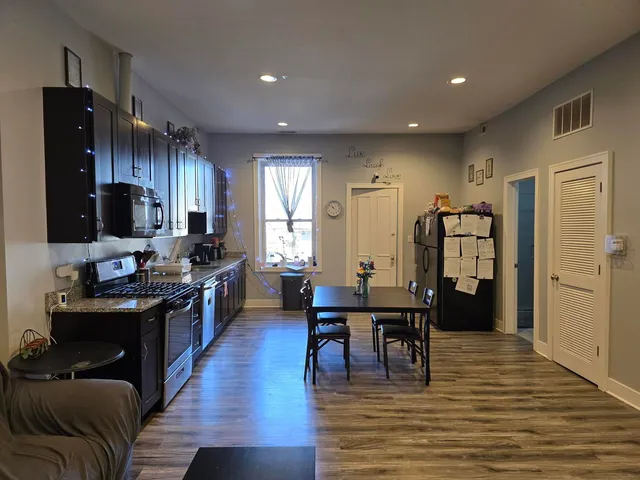 a kitchen with stainless steel appliances granite countertop a refrigerator dining table and chairs