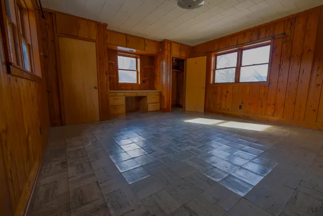 an empty room with windows cabinet and front door