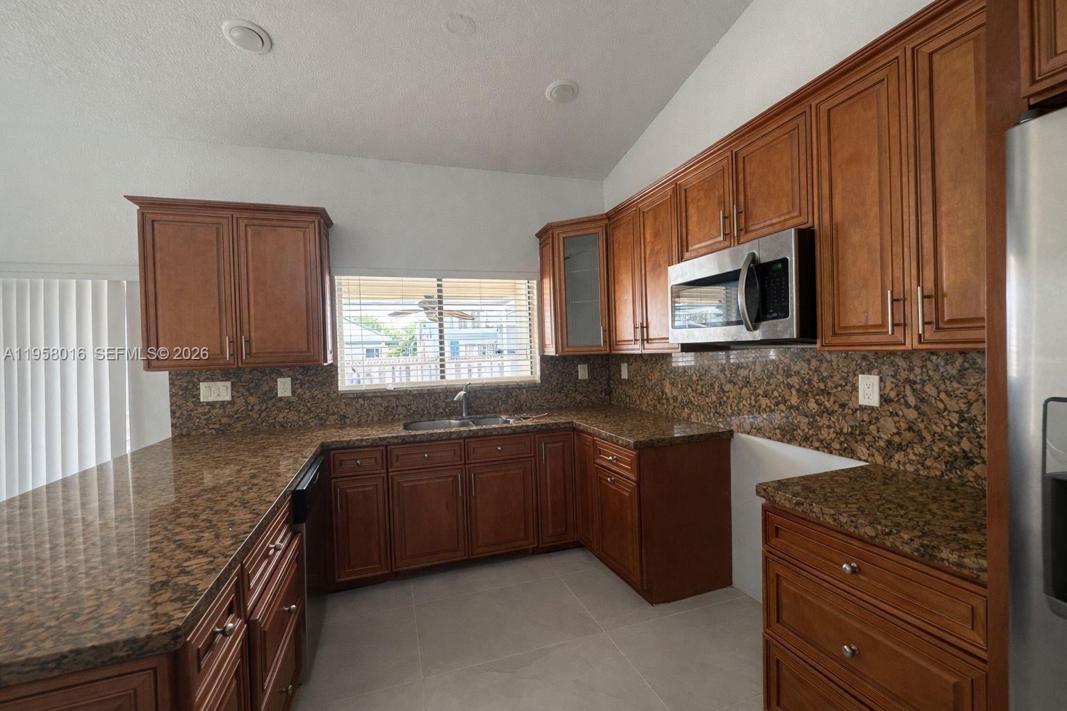 10034 Southwest 221st Street Cutler Bay, FL 33190 - Photo 5 of 25 a kitchen with stainless steel appliances granite countertop wooden cabinets a stove top oven a sink and dishwasher