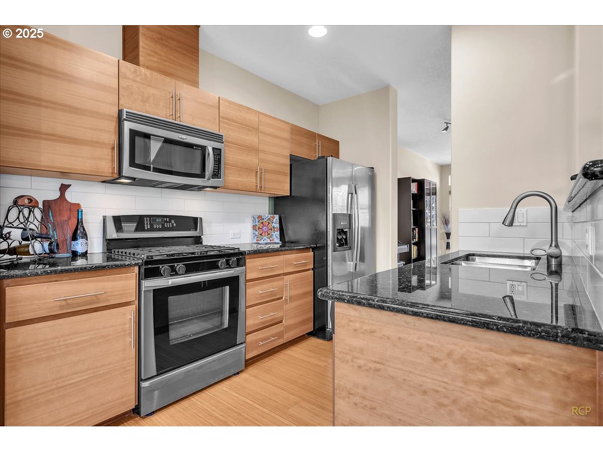 794 Northwest 118th Avenue, Unit 101 Portland, OR 97229 - Photo 15 of 41 a kitchen with stainless steel appliances granite countertop a stove a sink and a microwave