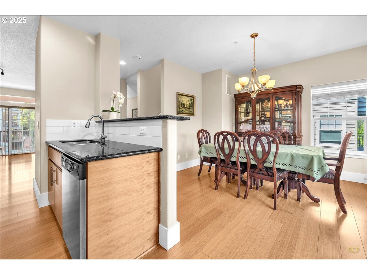 794 Northwest 118th Avenue, Unit 101 Portland, OR 97229 - Photo 17 of 41 a kitchen with stainless steel appliances kitchen island granite countertop a table chairs and a view of living room