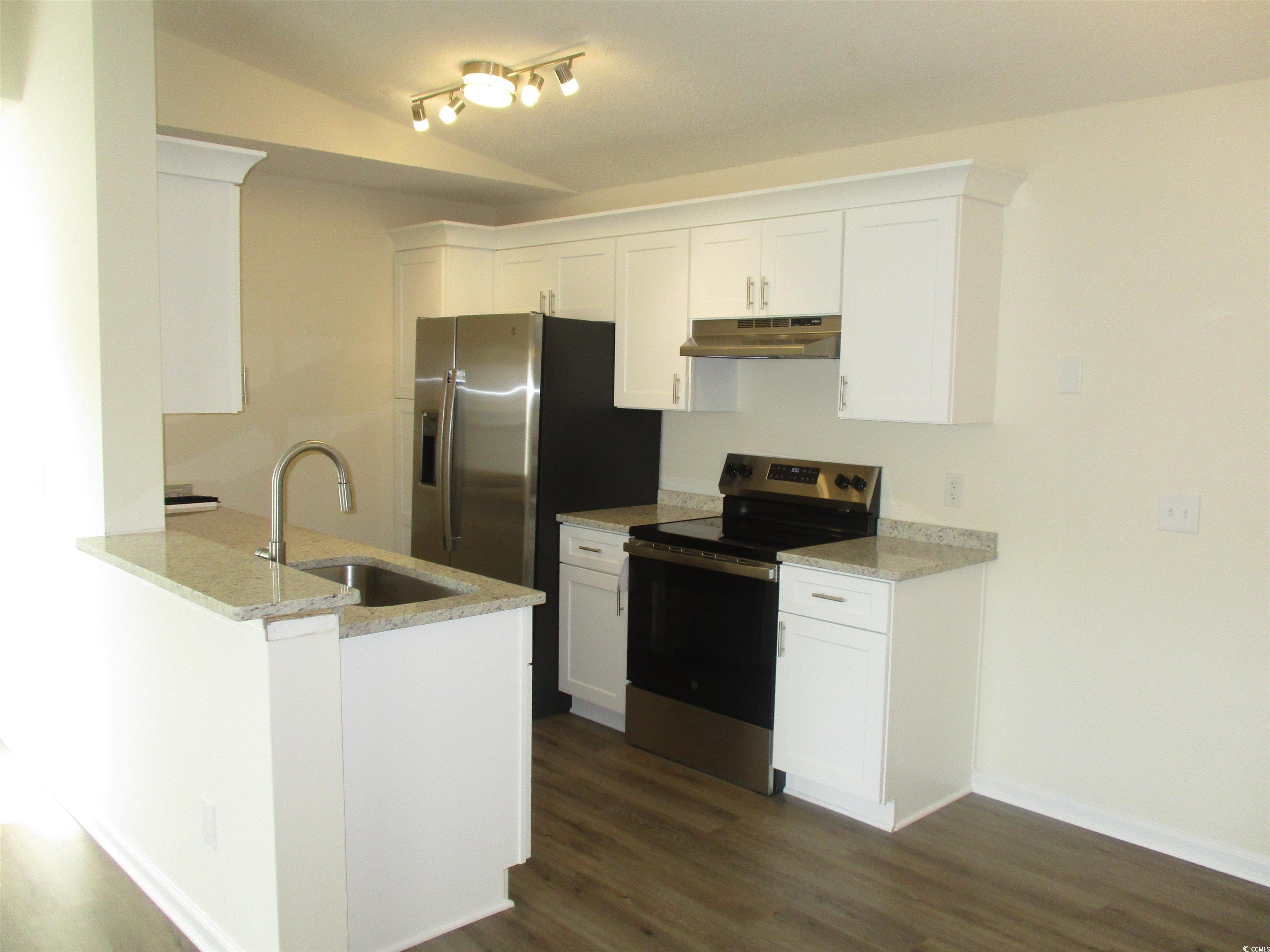 8545 Hopkins Circle Surfside Beach, SC 29575 - Photo 6 of 24 Kitchen with stainless steel appliances, light stone counters, white cabinets, under cabinet range hood, and a peninsula