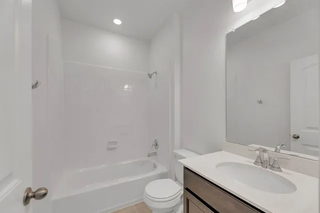 a bathroom with a bathtub shower sink vanity mirror and toilet