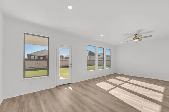 a view of an empty room with a window and wooden floor
