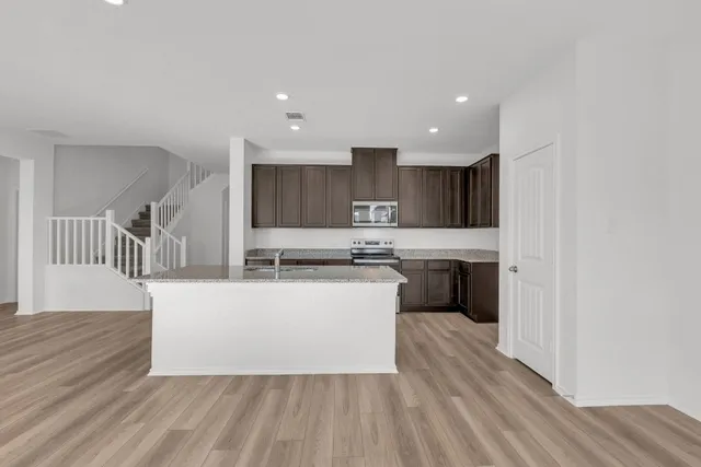 a large kitchen with stainless steel appliances a sink a stove a refrigerator and cabinets