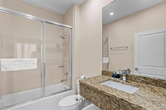 a bathroom with a granite countertop sink toilet and shower