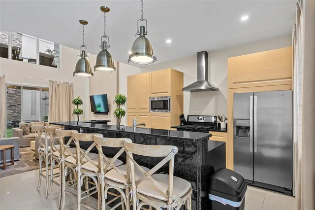 a kitchen with stainless steel appliances granite countertop a stove a refrigerator a sink a dining table and chairs with wooden floor