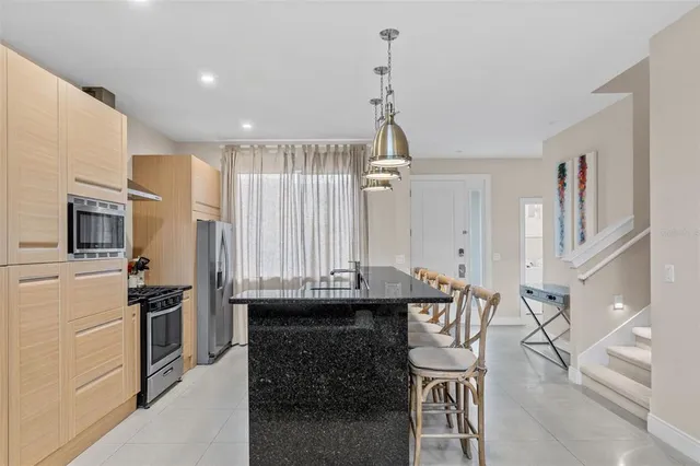 a kitchen with stainless steel appliances kitchen island granite countertop a refrigerator and a stove top oven