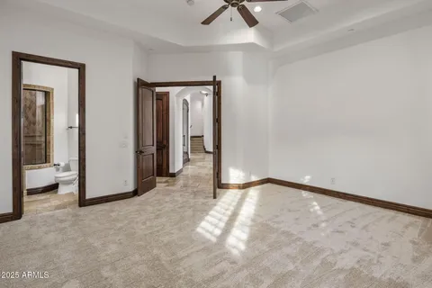 an empty room with wooden floor ceiling fan and windows