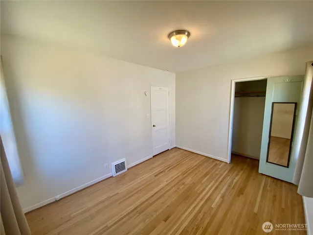 an empty room with wooden floor and entrance