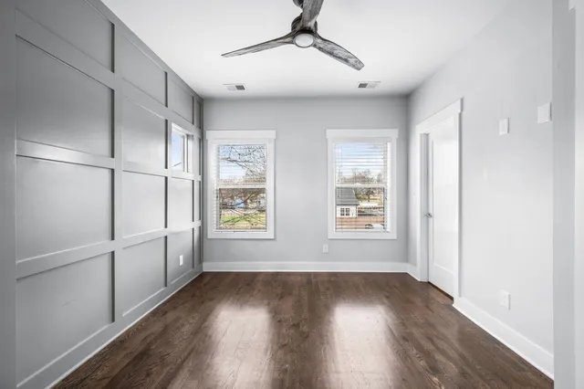 a view of empty room with wooden floor and fan
