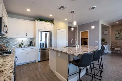 a kitchen with stainless steel appliances granite countertop a kitchen island hardwood floor sink stove dining table and chairs