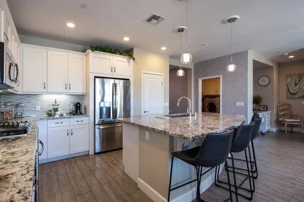 a kitchen with stainless steel appliances granite countertop a kitchen island hardwood floor sink stove dining table and chairs