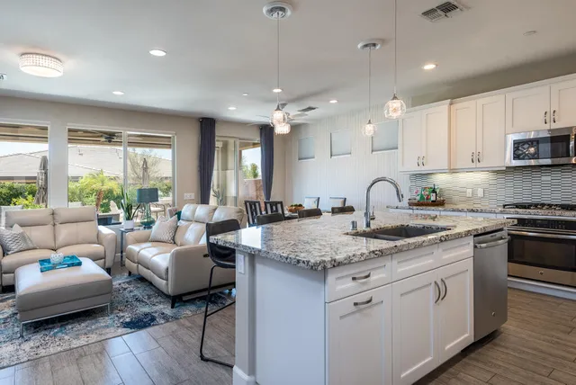 a kitchen with sink stove and white cabinets with wooden floor