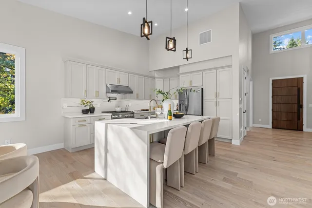 a kitchen with stainless steel appliances kitchen island granite countertop a refrigerator a stove a sink a dining table and chairs with wooden floor