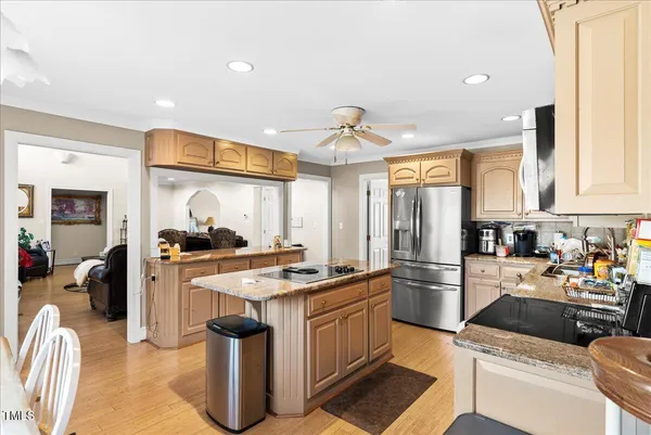 a kitchen with stainless steel appliances granite countertop a stove top oven a sink dishwasher and a refrigerator with wooden floor