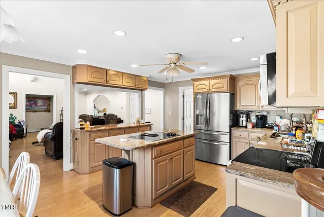 a kitchen with stainless steel appliances granite countertop a stove top oven a sink dishwasher and a refrigerator with wooden floor