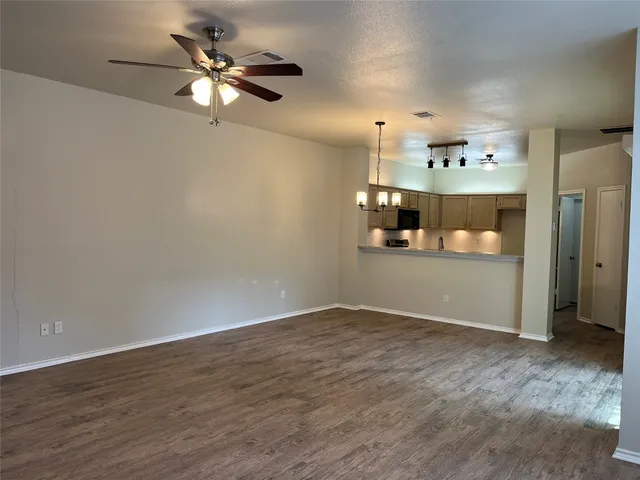 an empty room with wooden floor and fan