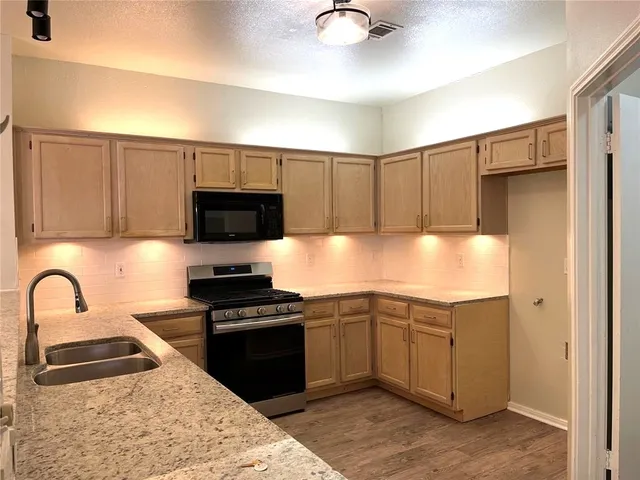 a kitchen with granite countertop a sink stainless steel appliances and cabinets