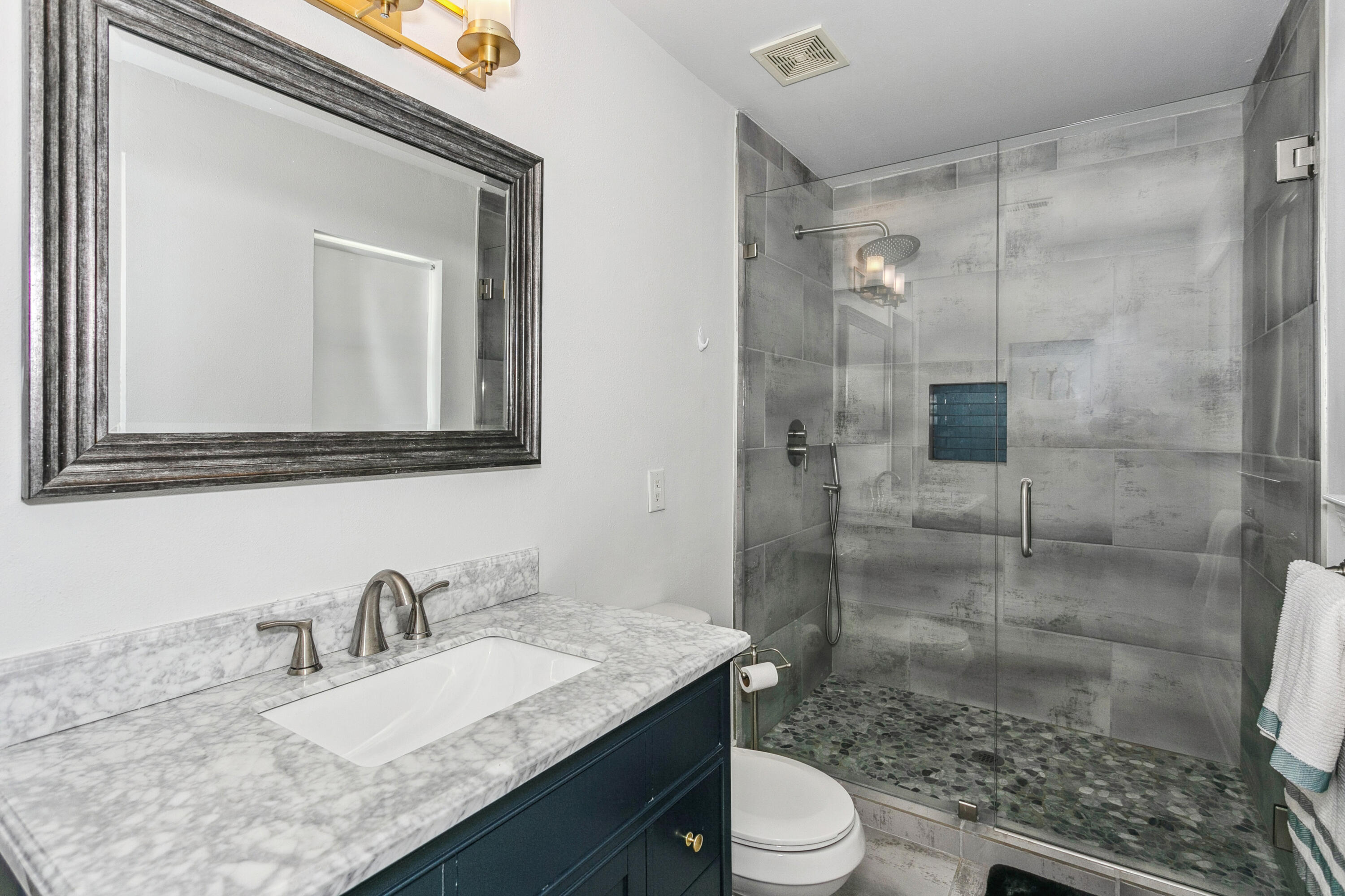 7905 White Sands Boulevard, Unit 2 Navarre, FL 32566 - Photo 25 of 51 a bathroom with a granite countertop sink mirror toilet and shower