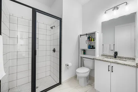a bathroom with a granite countertop sink toilet a mirror and shower